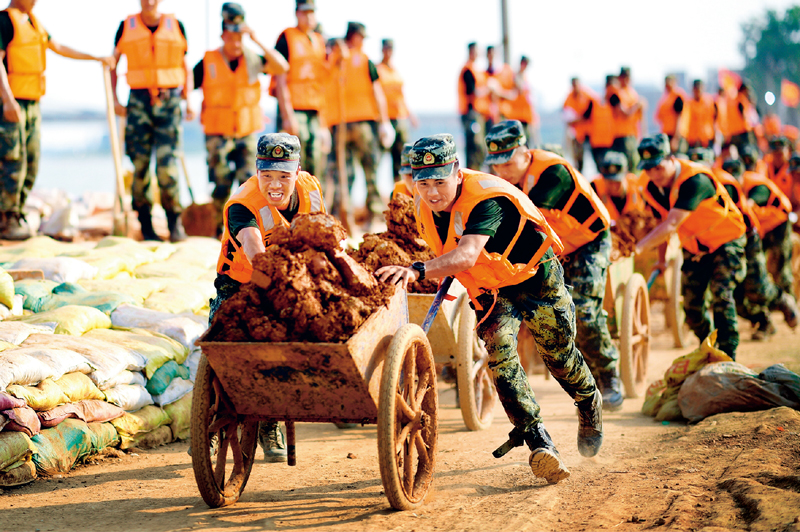 2020年7月以来,我国多地遭遇持续强降雨,发生严重洪涝灾害。人民至上、生命至上。提前转移、紧急营救🧑🏭、妥善安置……一场涉及上百万群众生命的生死竞速就此拉开👨💻。图为2020年7月17日,武警江西总队机动支队党员突击队在江西省鄱阳县鄱阳镇昌江圩用推车将余土推到空地堆放。 新华社发 曹先训/摄
